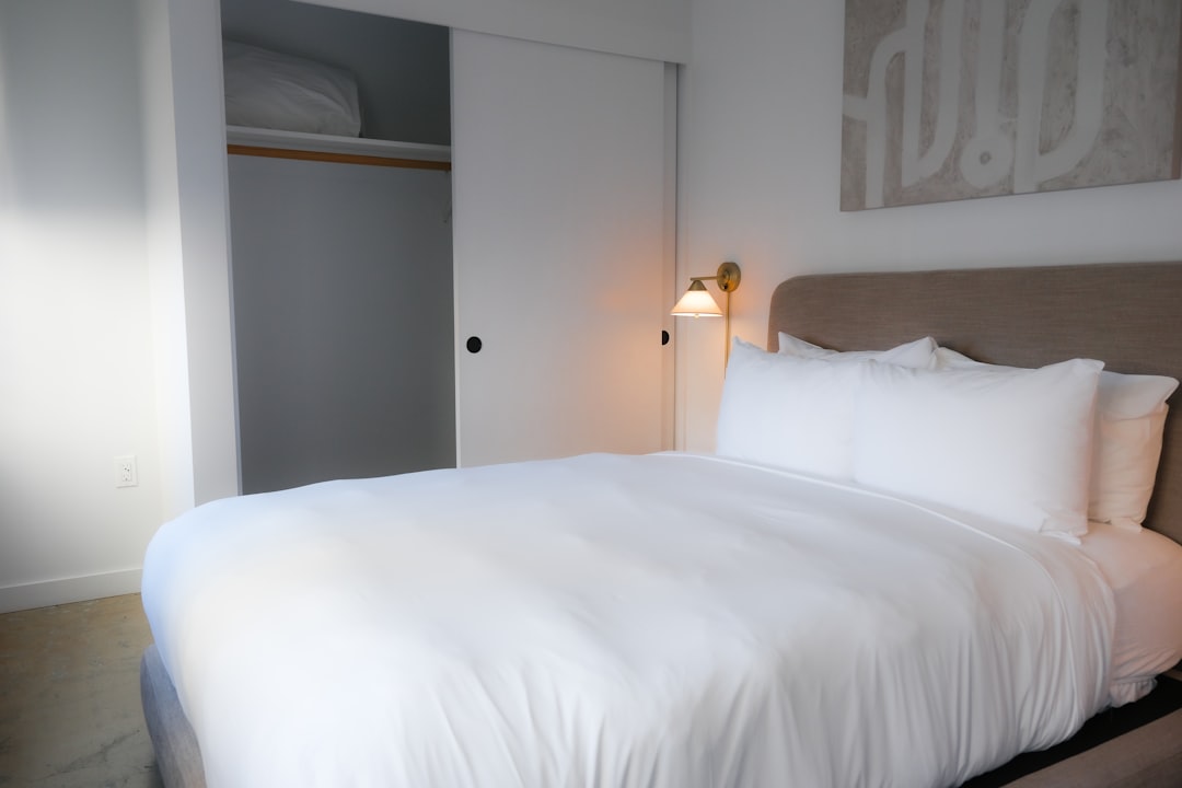 a-neatly-made-bed-with-white-linens-in-a-bedroom-a2lzyq8nt-e